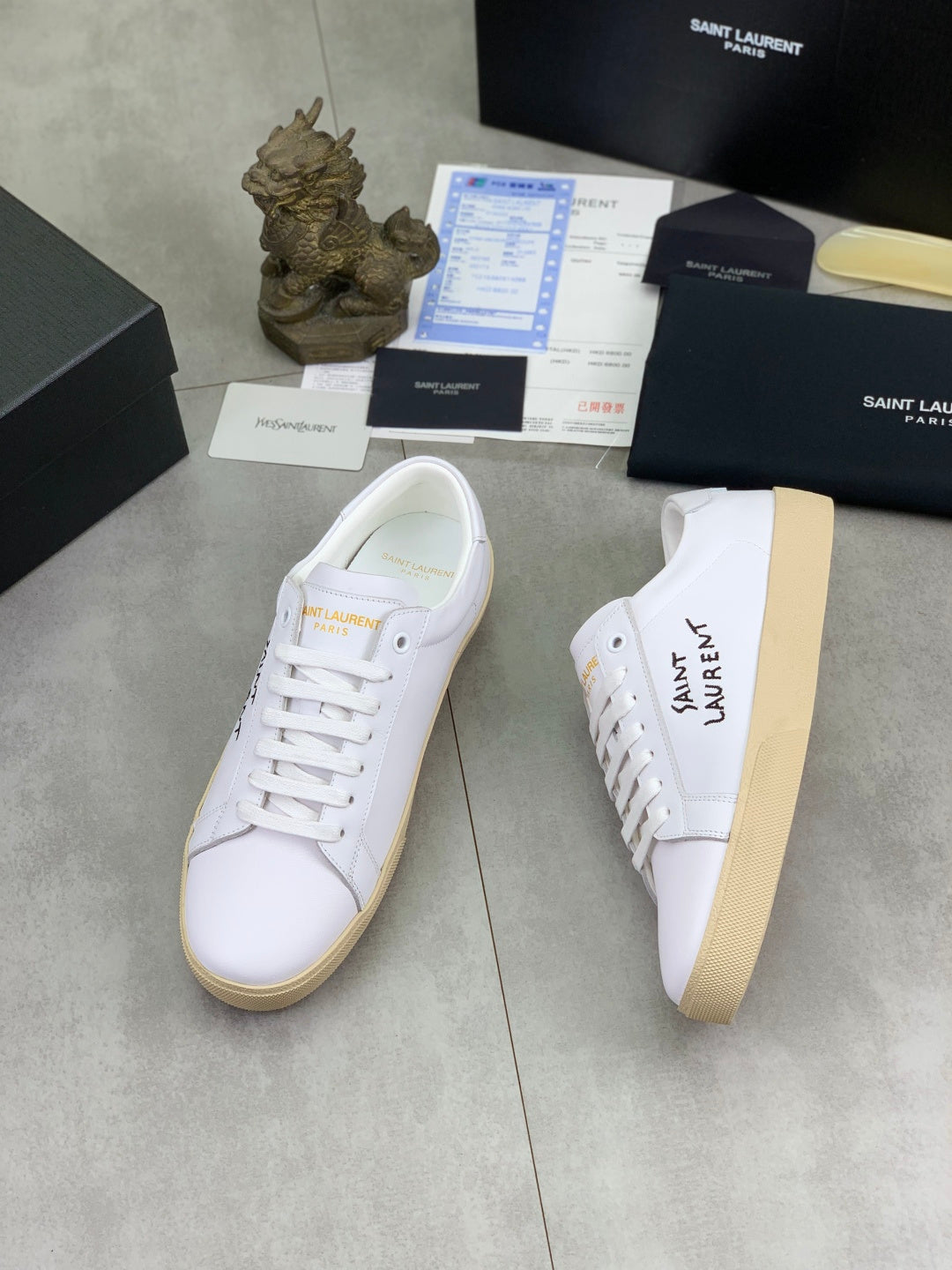 White YSL unisex sneakers on shoebox, one angled side view with gum sole
