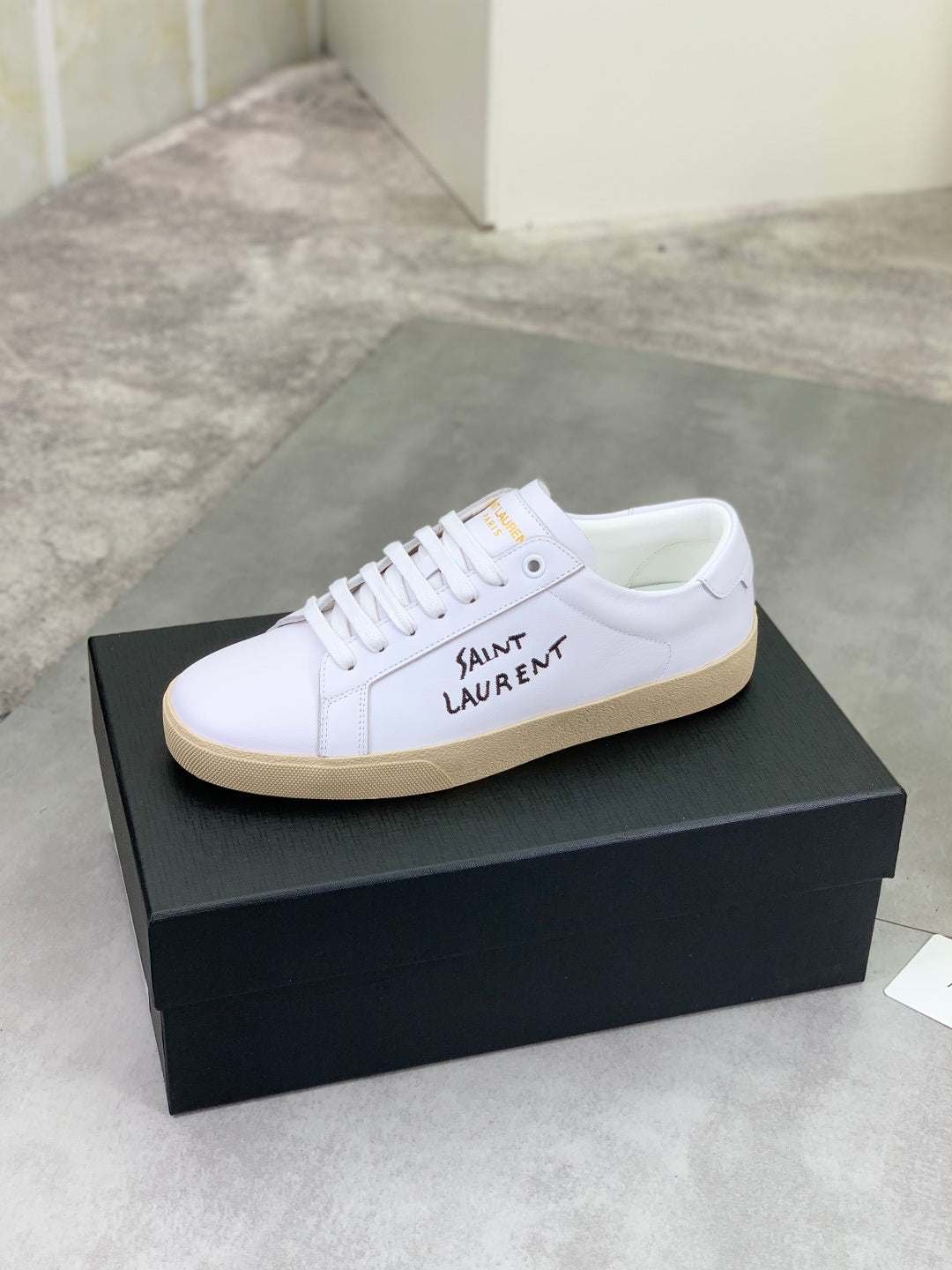 White YSL unisex low-top sneakers with lace-up and gum sole on black box