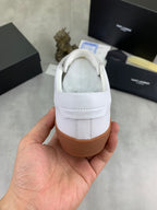 Back view of white low-top sneaker with padded collar and tan rubber sole