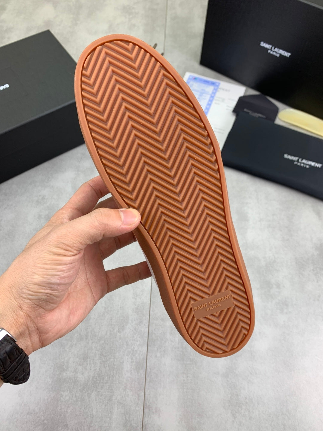 Outsole of white low-top sneaker showing brown zigzag tread pattern
