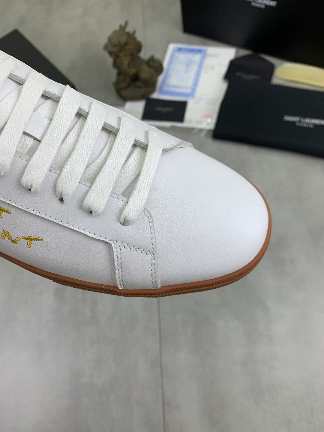 Close-up of white low-top sneaker with white laces and tan rubber sole edge