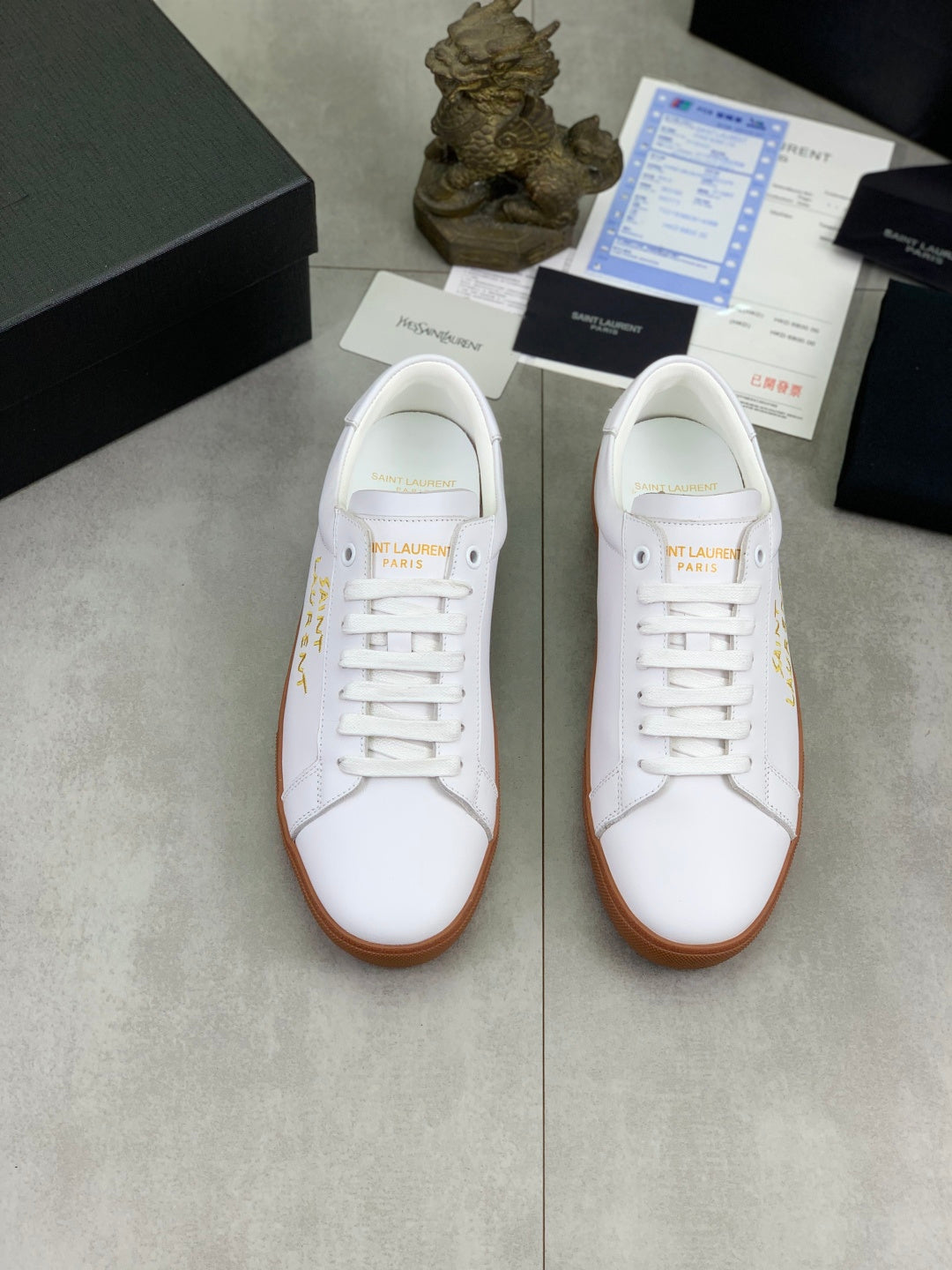 Pair of white low-top sneakers with white laces and tan rubber soles