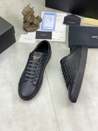 Dark leather lace-up sneakers showing side logos and textured heel area.