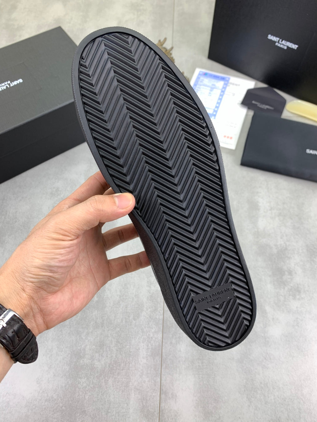 Rubber outsole of dark leather sneakers with zigzag chevron tread pattern.
