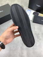 Rubber outsole of dark leather sneakers with zigzag chevron tread pattern.