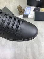 Close-up of dark gray leather sneaker toe with lace-up eyelets and stitching.