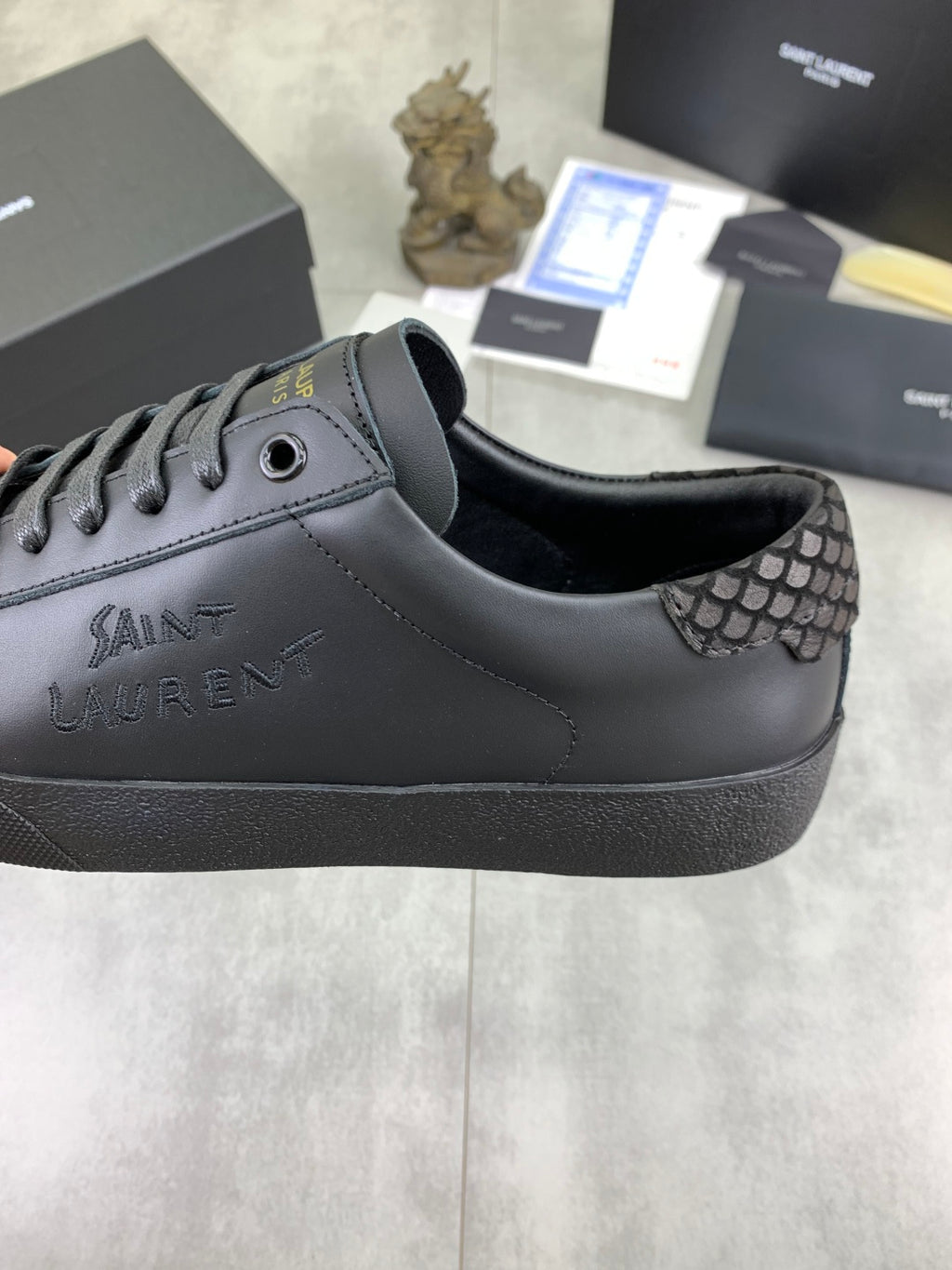 YSL sneakers with dark leather upper and patterned side panel near the eyelets.