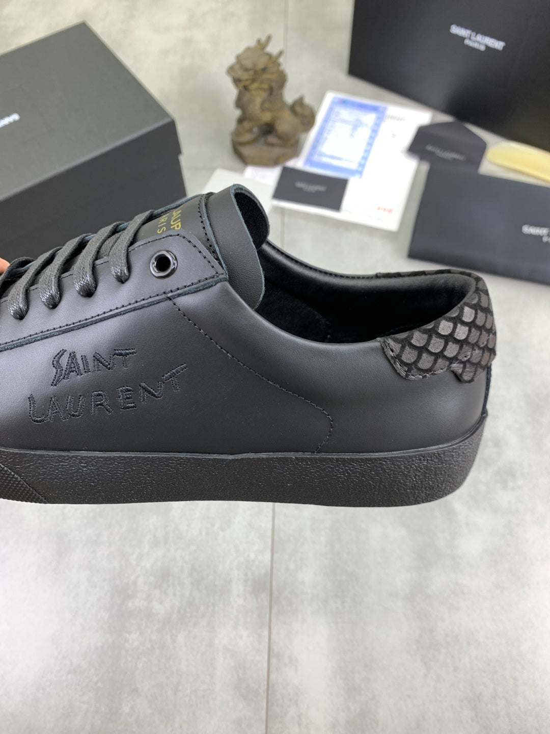 YSL sneakers with dark leather upper and patterned side panel near the eyelets.