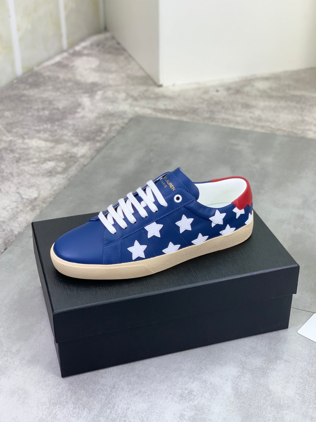Blue low-top sneakers with white stars, red collar trim, beige rubber sole