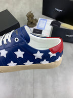 Blue sneaker with white stars, white laces, and red heel collar accent