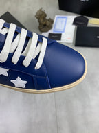 Close-up of blue sneaker toe with white star patch and white laces, beige sole