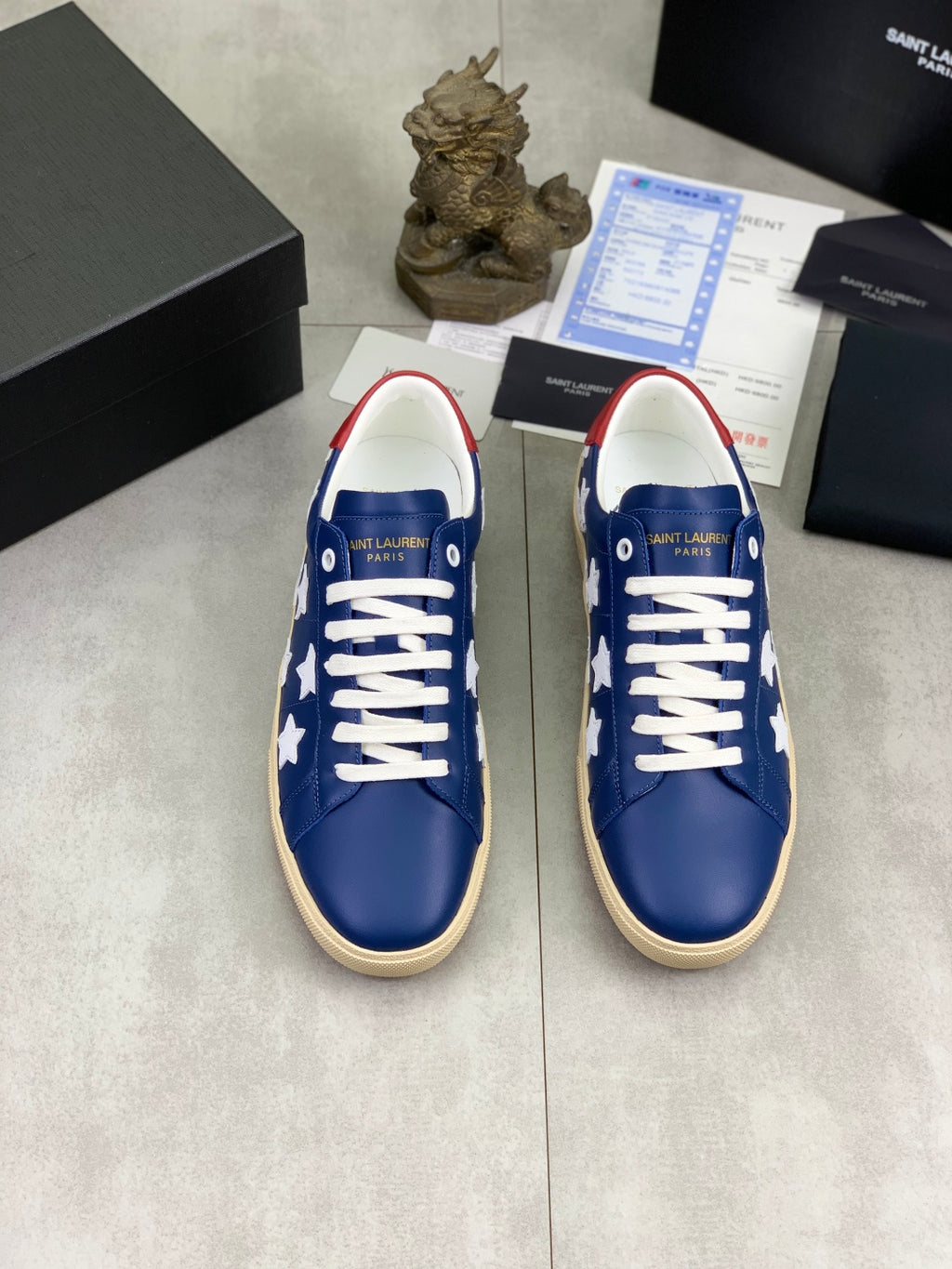 Pair of blue low-top sneakers with white stars and white laces, beige soles