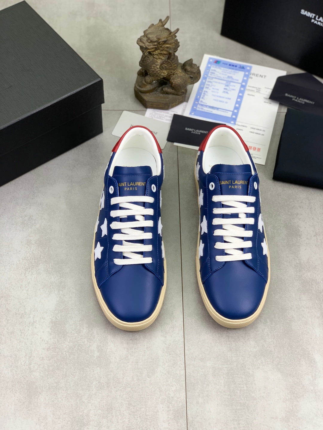 Pair of blue low-top sneakers with white stars and white laces, beige soles