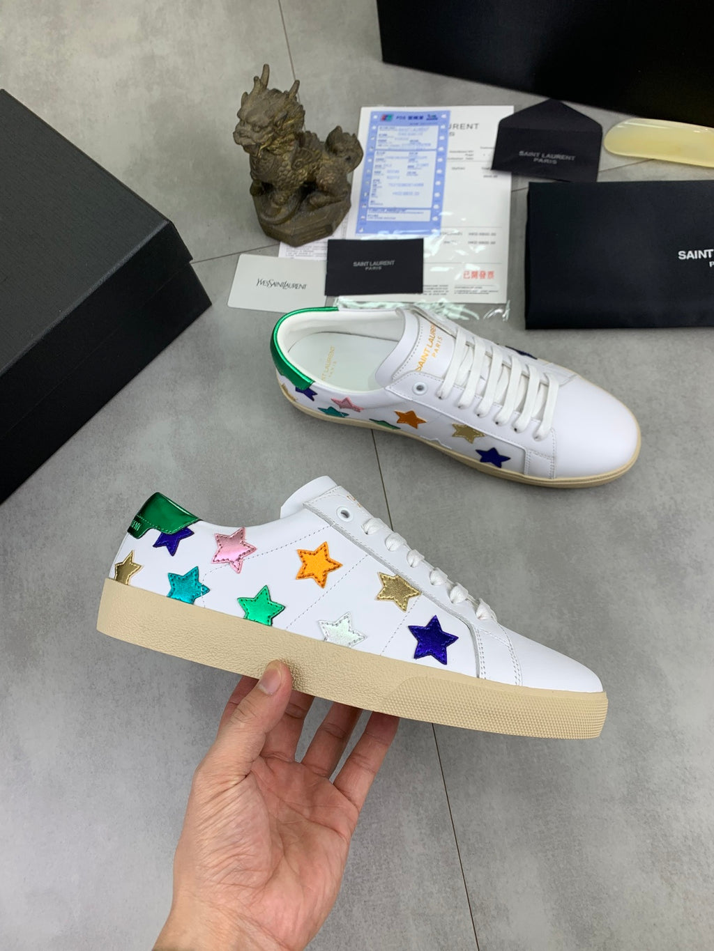 Unisex low-top sneakers laid out: multicolor stars on white with green inner trim