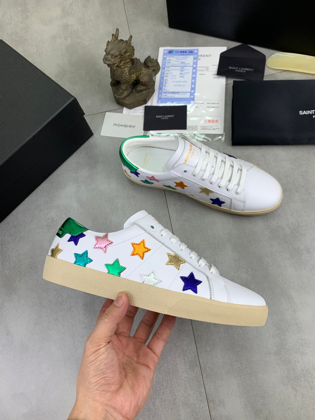 Unisex low-top sneakers laid out: multicolor stars on white with green inner trim