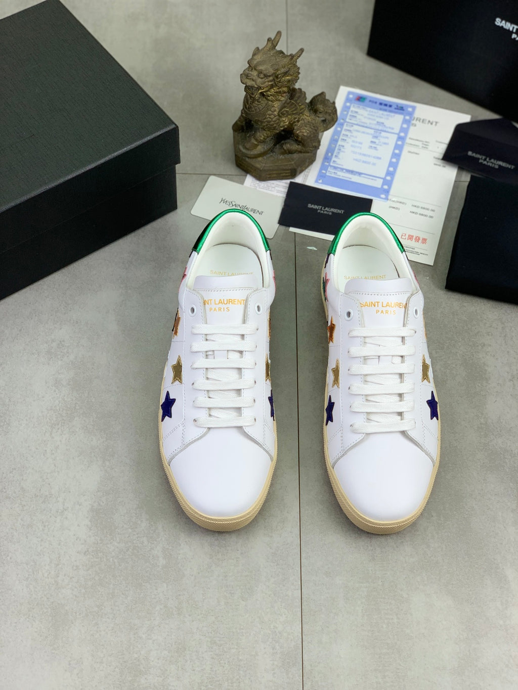 Pair of unisex low-top sneakers with white uppers and colorful star decorations, gum sole