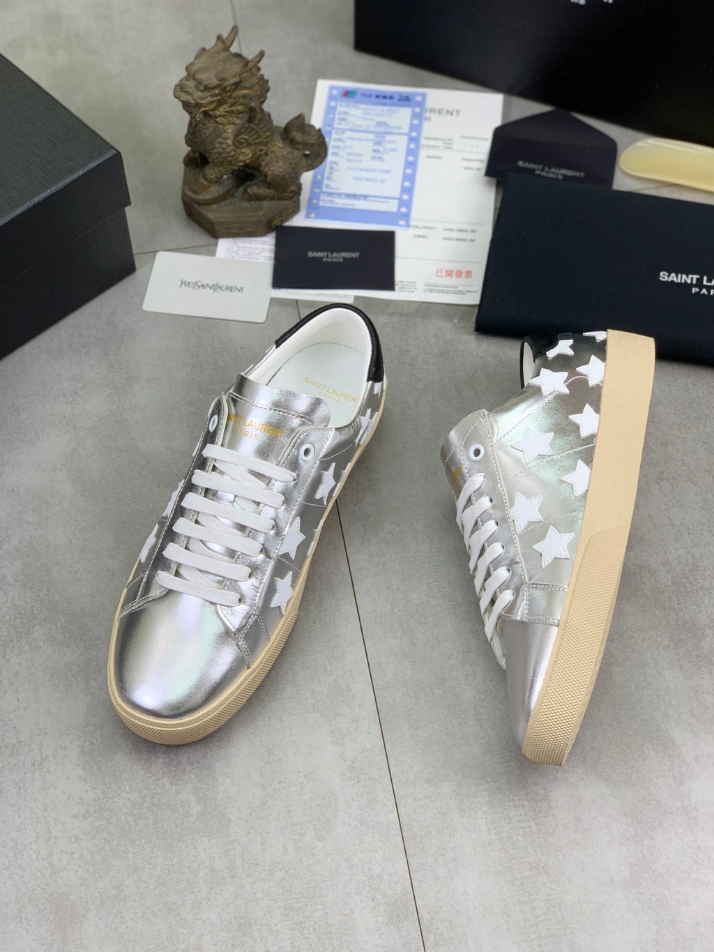 YSL unisex low-top sneakers shown angled, silver with white star details, white laces, gum sole
