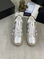 YSL unisex low-top sneakers pair, silver uppers with white star pattern, white laces, gum sole
