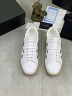 Pair of unisex white sneakers with gray stars and white laces on beige soles