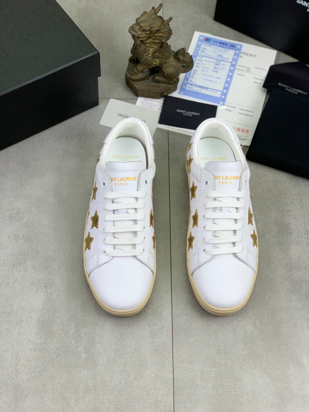 Pair of white low-top sneakers with gold stars and beige rubber soles
