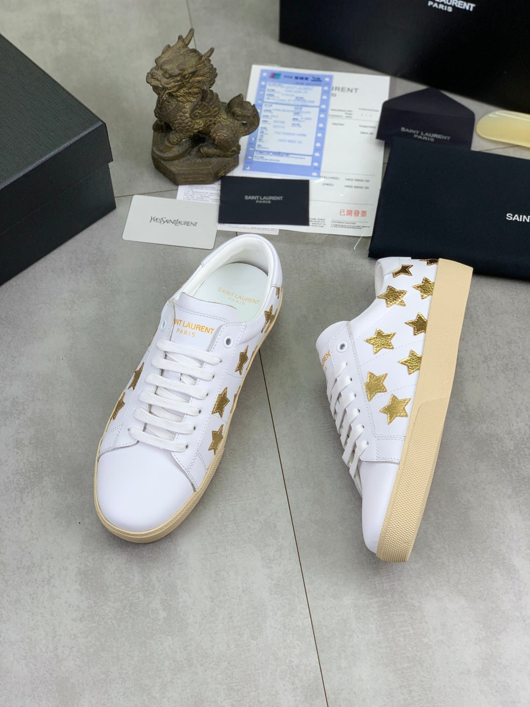 White low-top sneakers with gold star appliques and beige platform sole