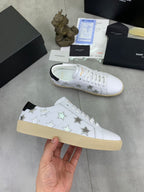 YSL unisex luxury shoes: white sneakers with star print and tan sole, hand-held view