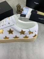 White low-top sneakers with gold stars on side, padded collar, and beige sole
