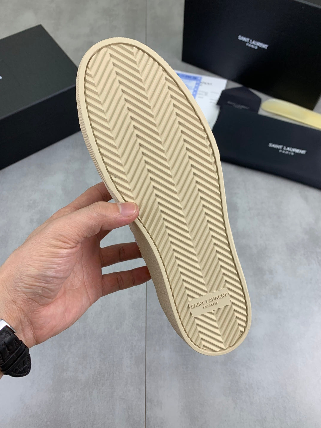 Bottom tread of white low-top sneakers with beige chevron rubber sole