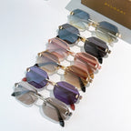 Stack of tinted sunglasses with gold frames in blue, pink, and purple shades
