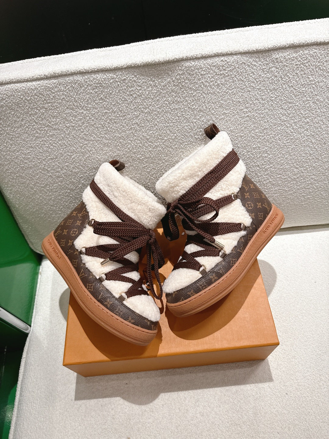 Louis Vuitton high-top sneakers close-up: brown monogram laces and white sherpa cuffs