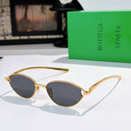 Bottega Veneta sunglasses with gold frame and dark tinted oval lenses