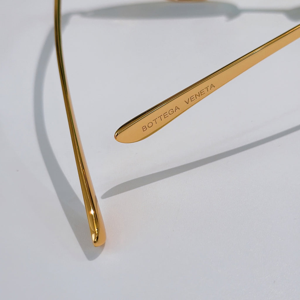 Bottega Veneta sunglasses: close-up gold temple arm with BOTTEGA VENETA lettering