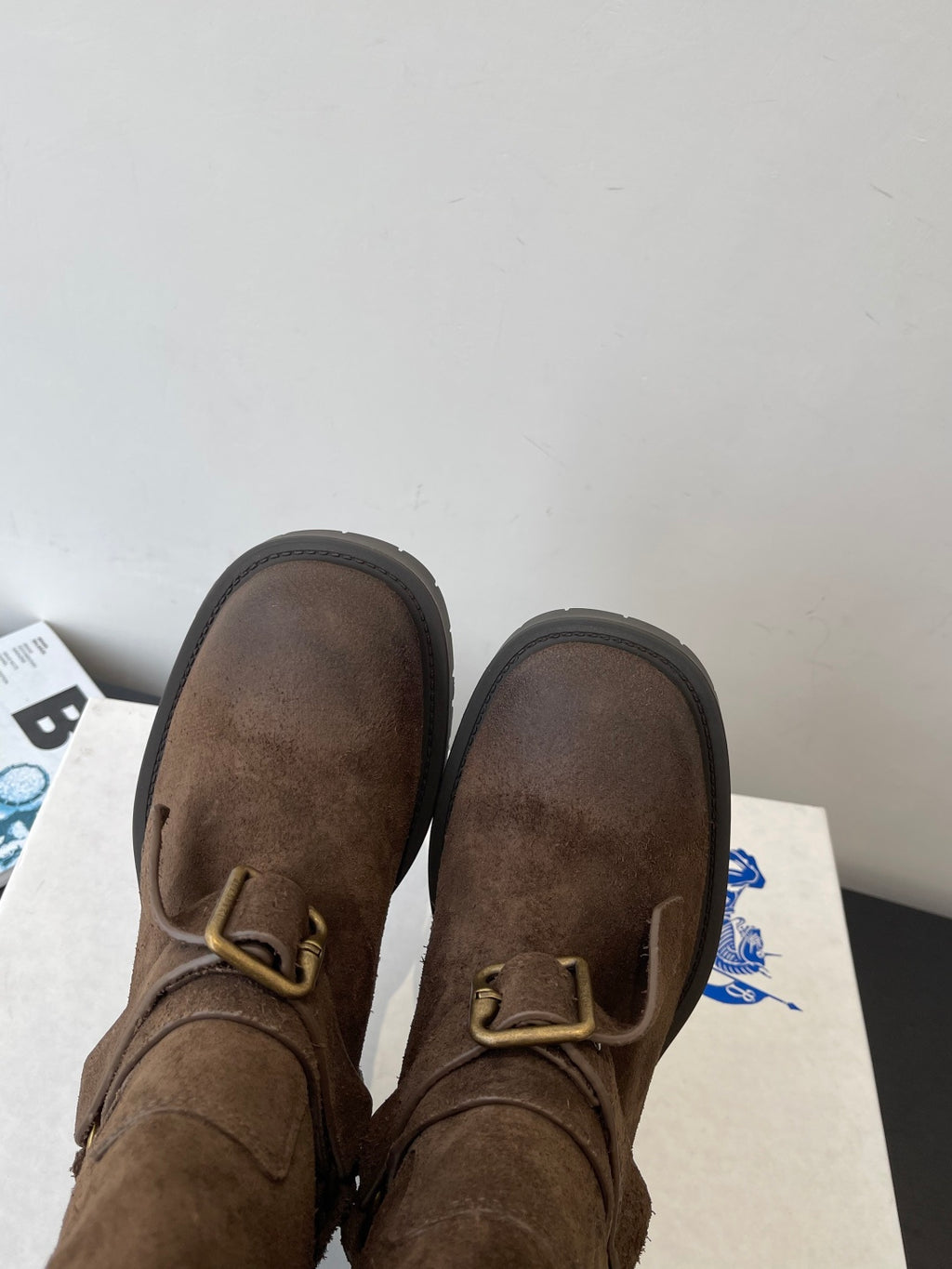 Burberry dark brown suede boots with buckle strap, close-up with soles up