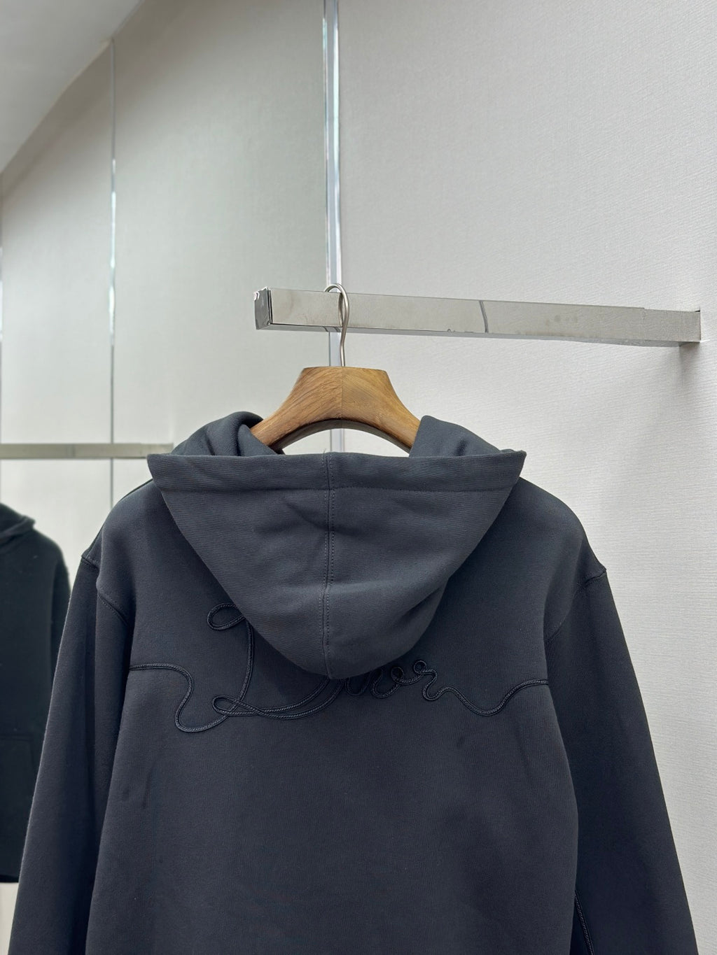 Dark blue hoodie back view with hood and embroidered logo, on hanger