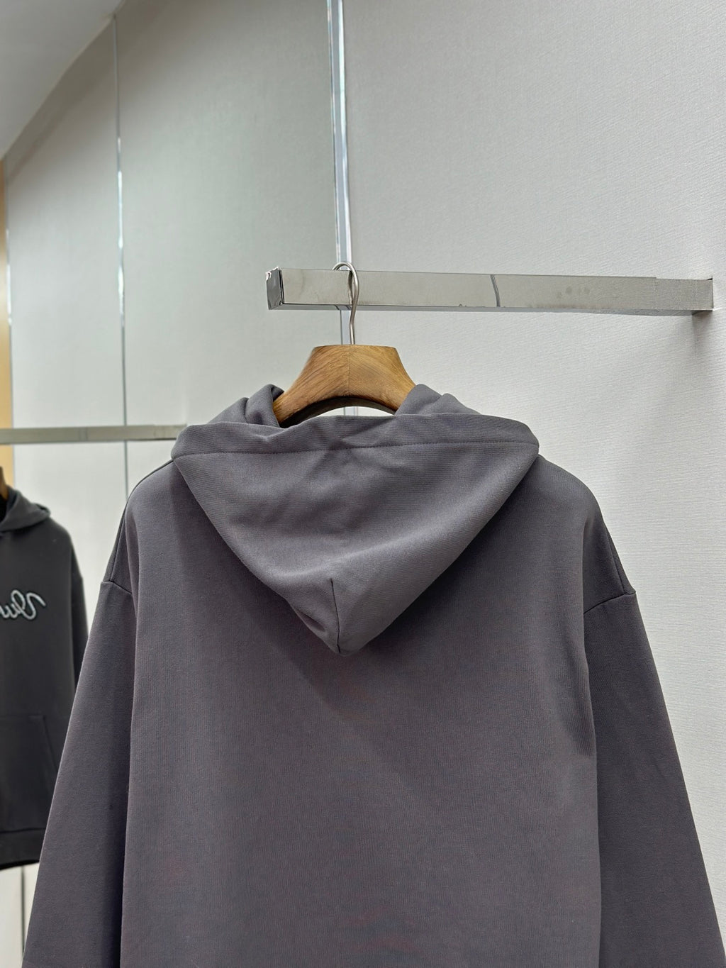 Dark gray hooded long-sleeve hoodie with back drape on hanger