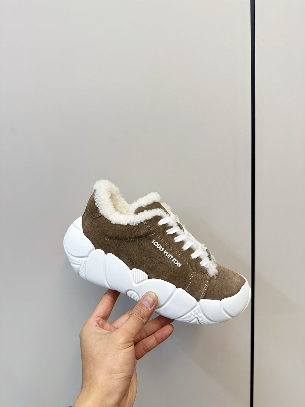 Brown sneakers with plush collar, white laces, and chunky white sole (held)