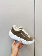 Brown sneakers with plush collar, white laces, and chunky white sole (held)