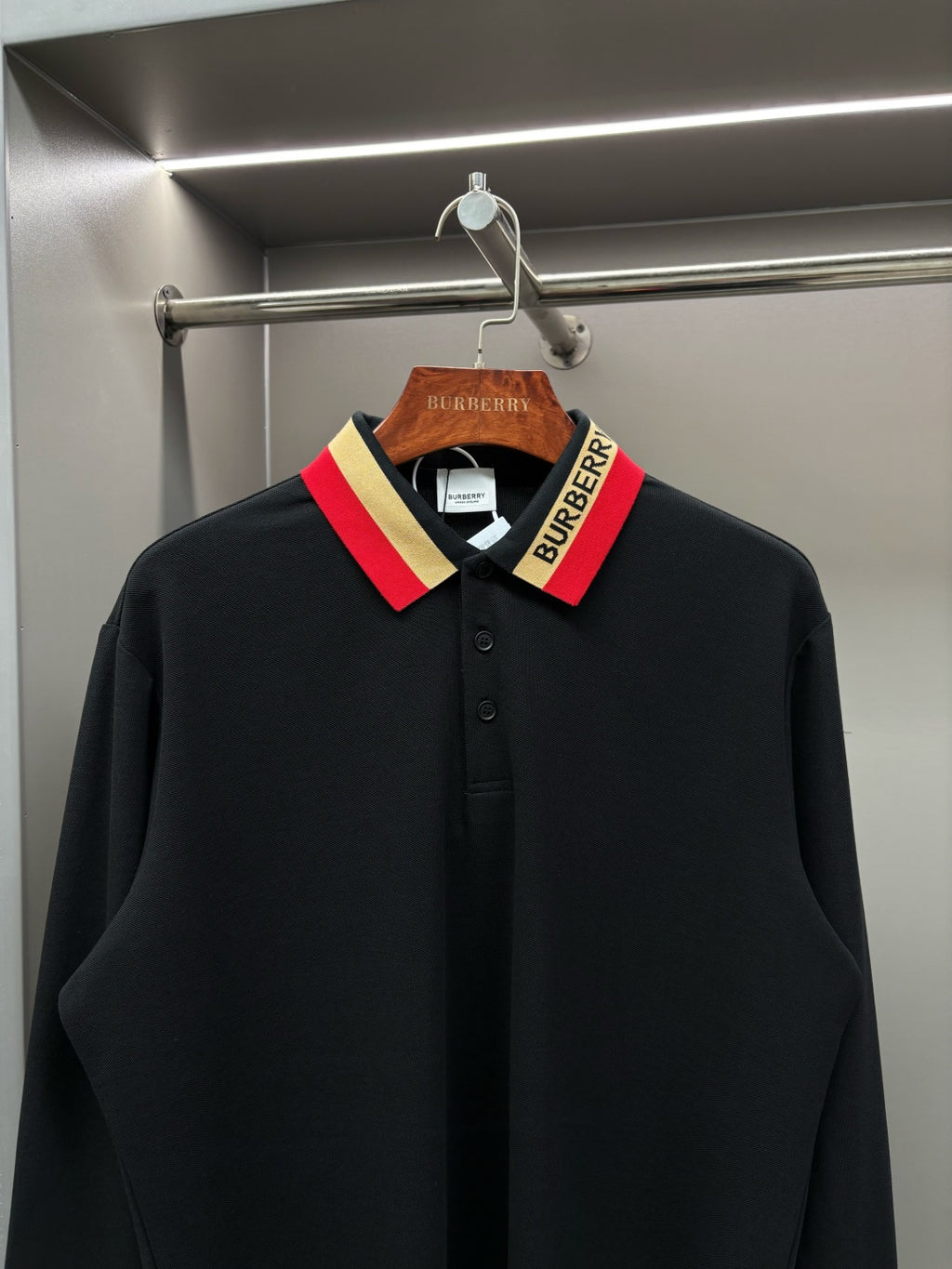 Black long-sleeve polo shirt with striped collar and buttoned neckline detail