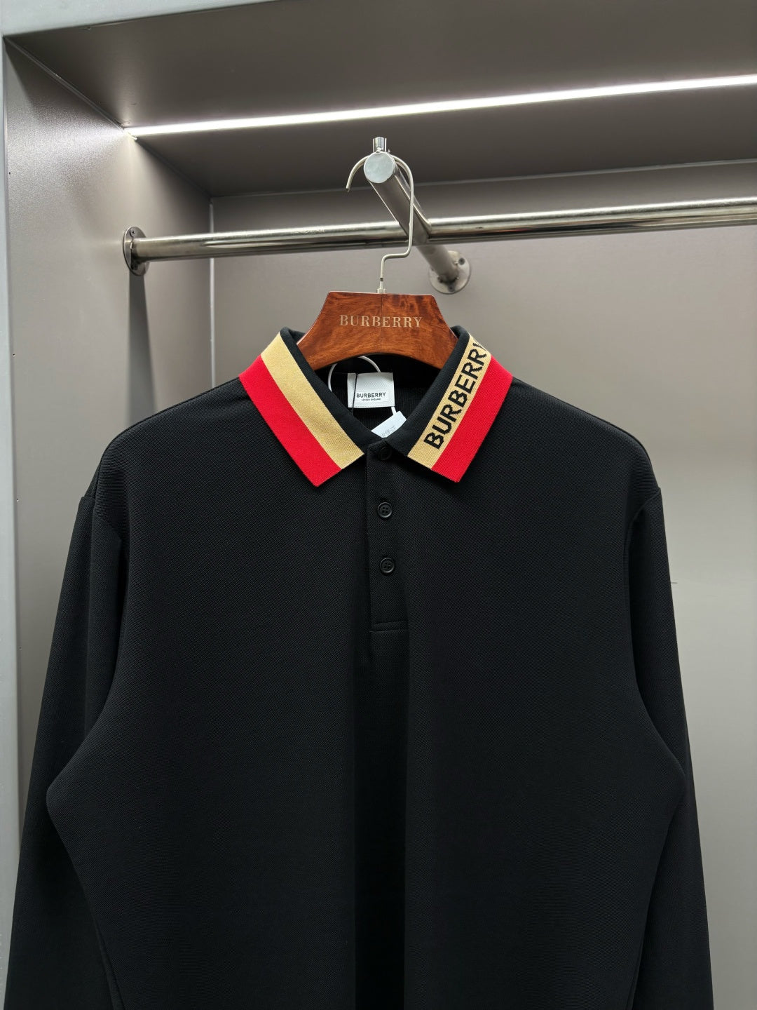 Black long-sleeve polo shirt with striped collar and buttoned neckline detail