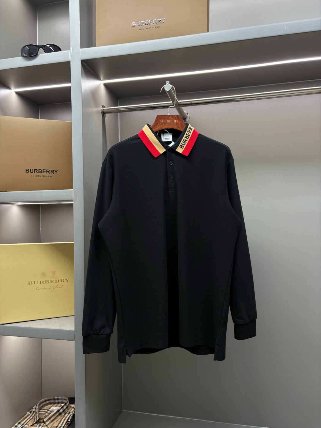 Long-sleeve black polo shirt with button placket and multicolor striped collar