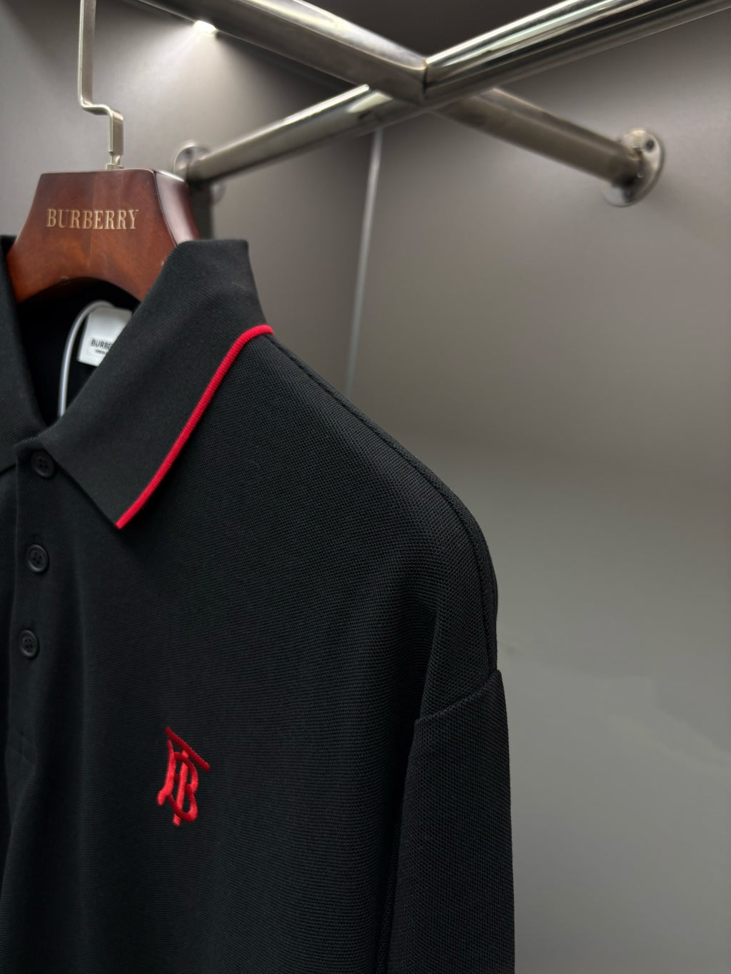 Long-sleeve polo shirt side view with small monogram logo on dark black fabric
