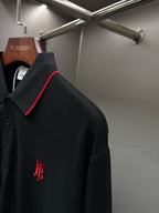 Long-sleeve polo shirt side view with small monogram logo on dark black fabric