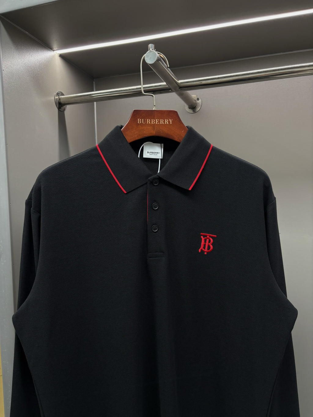 Long-sleeve polo shirt with red-trim collar, button placket, and chest monogram logo