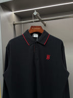 Long-sleeve polo shirt with red-trim collar, button placket, and chest monogram logo