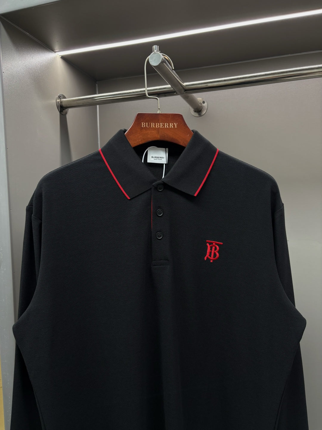 Long-sleeve polo shirt with red-trim collar, button placket, and chest monogram logo