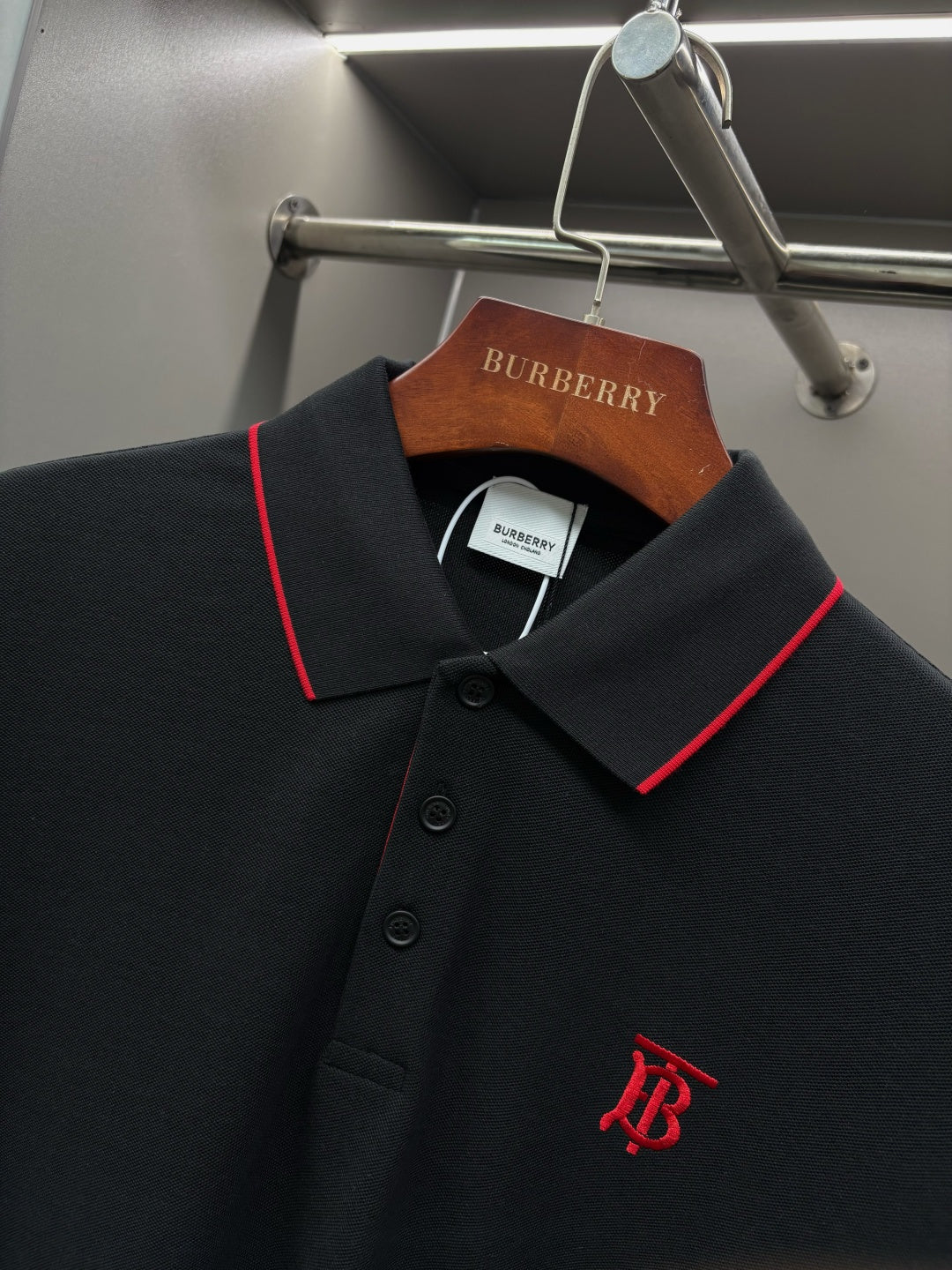 Long-sleeve polo shirt collar close-up with red trim, buttons, and monogram logo