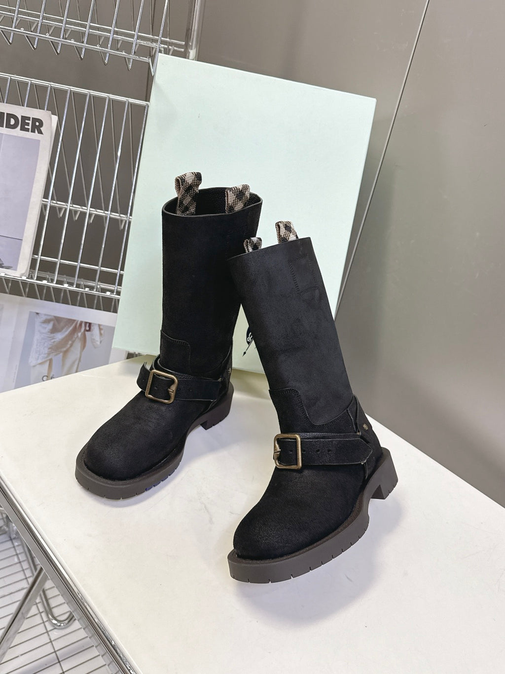 Pair of black suede mid-calf boots with buckled straps and rubber lug sole