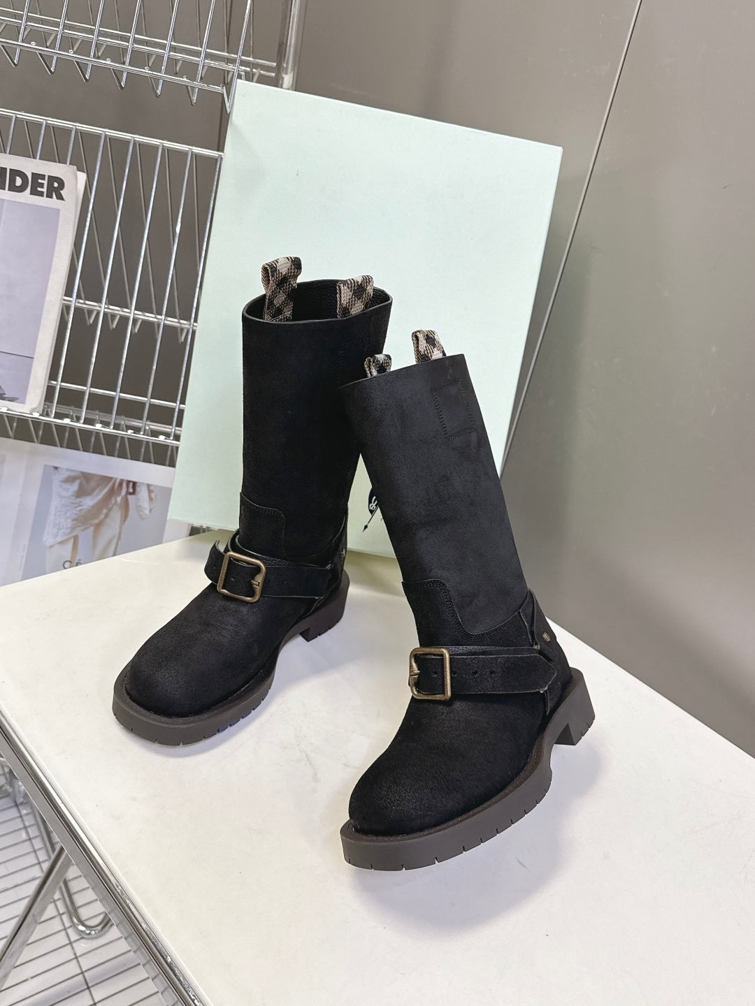 Pair of black suede mid-calf boots with buckled straps and rubber lug sole