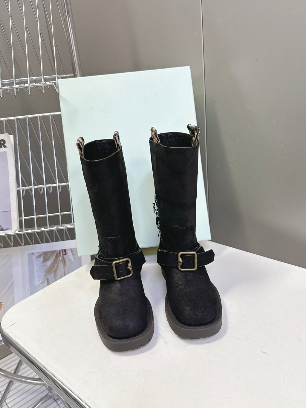 Pair of black suede ankle boots with side buckle and short stacked heel