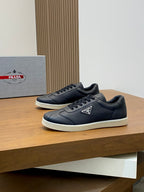 Prada unisex low-top sneakers pair, dark navy leather, lace-up, logo tongue patch